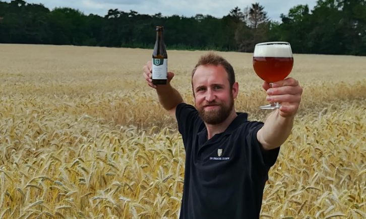 Bram van Heische Hoeve brouwerij Bram van Heische Hoeve brouwerij in een veld vol graan met bier in de hand